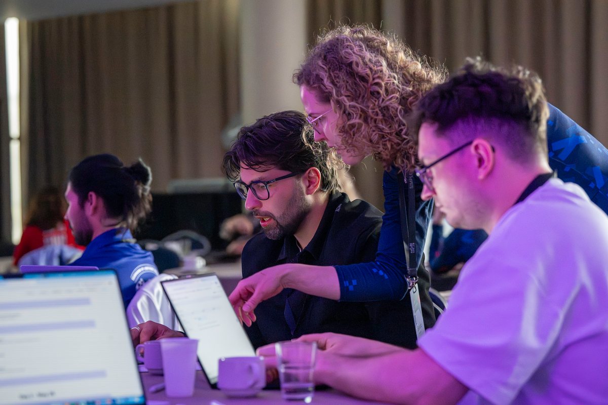 A mentor helping attendees at their laptops during the hands-on workshop